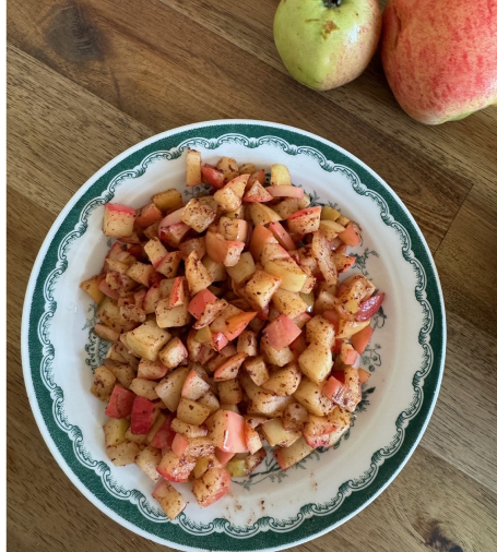 En djup skål med tärnade äpplen med krydda på.